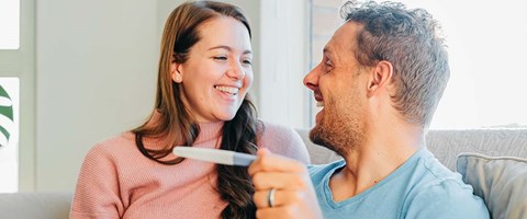 lykkelig mann og kvinne med graviditetstest. 