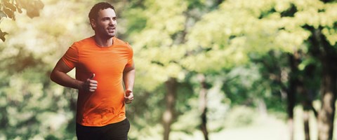 Mann  i oransje t-skjorte som løper utendørs. foto. 