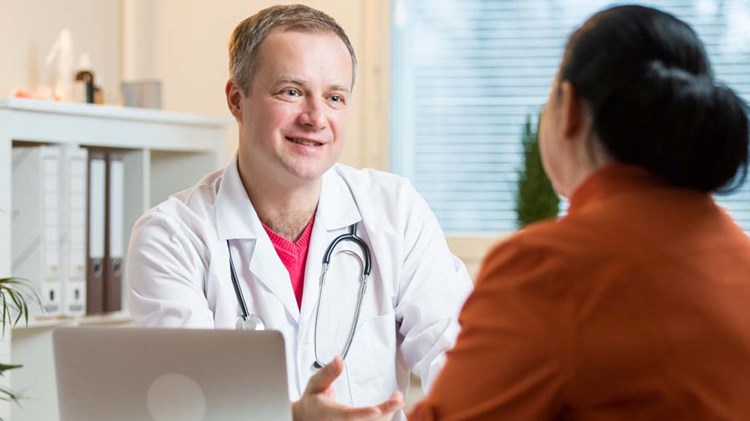 mannlige lege som konsulterer kvinnelig pasient på legekontor. 