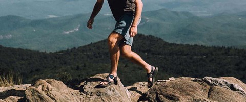 mann i shorts går tur i fjellterreng etter fjerning av åreknuter. Foto. 