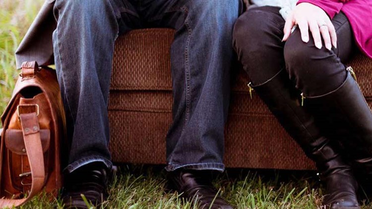 mann og kvinne sitter på en benk på en gresslette.