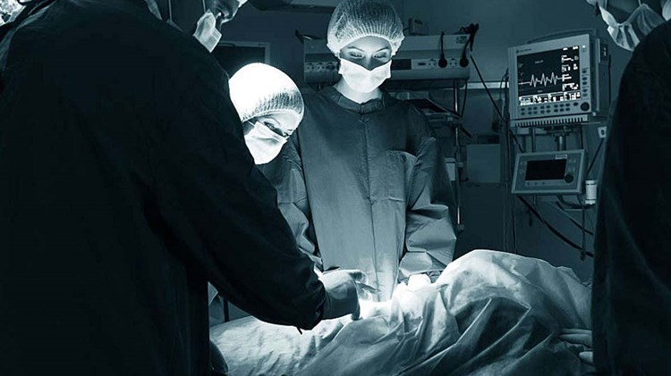 leger og sykepleiere opererer på pasient i dunkel belysning. Foto.