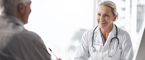 En kvinnelig lege smiler til pasient.